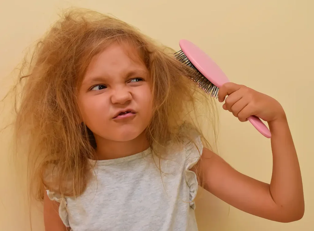 young girl trying to brush through very tangled hair