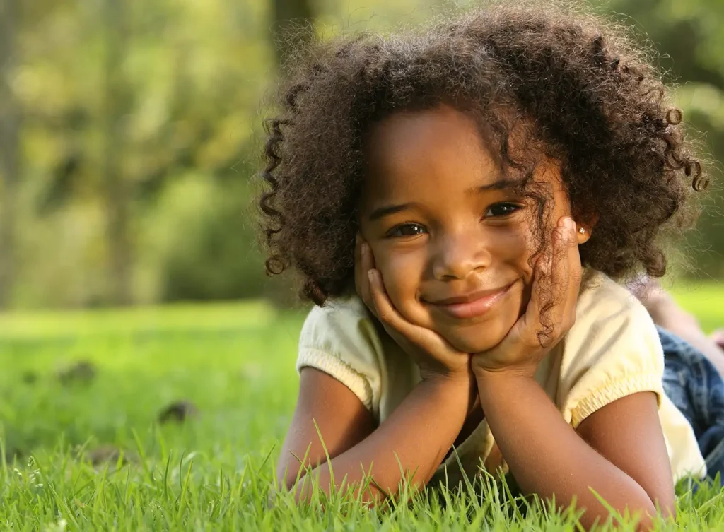 young black girl smiling while laying on the grass